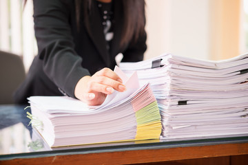 Asian business woman office workers holding are arranging documents of unfinished documents on office desk,Stack of business paper,document management,Businesswoman examining documents