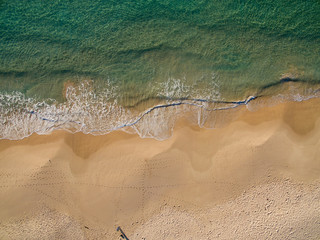 Aerial view of sandy beach as waves break on the shoreline