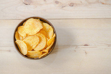 Crispy potato chips in brown cup On brown ground