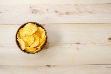 Obraz na płótnie Canvas Crispy potato chips in brown cup On brown ground