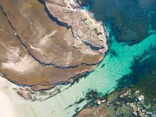 Aerial view of sandy coastline with large granite rock shelf