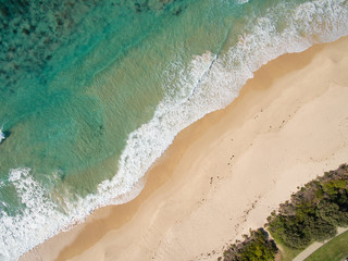 Aerial view of sandy beach as waves break on the shoreline
