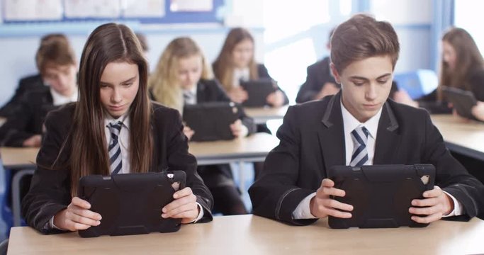 4k, Students using a digital tablet while studying in a classroom. Slow motion.