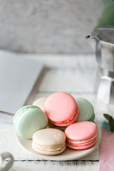 Colorful French or Italian macarons stack on white plate put on wood table with copy space for background. Dessert for served with afternoon tea or coffee break. Beautiful meal background with blank.