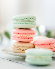 Colorful French or Italian macarons stack on white plate put on wood table with copy space for background. Dessert for served with afternoon tea or coffee break. Beautiful meal background with blank.