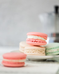 Colorful French or Italian macarons stack on white plate put on wood table with copy space for background. Dessert for served with afternoon tea or coffee break. Beautiful meal background with blank.