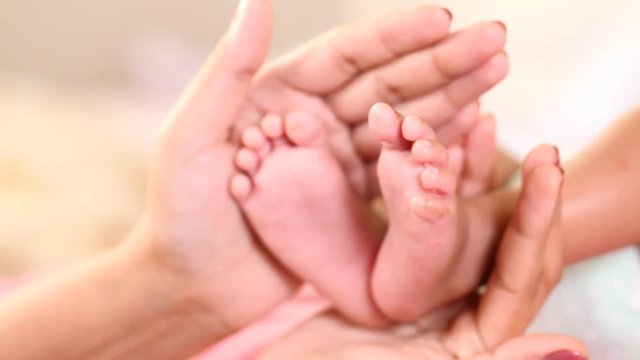 Newborn baby's legs in mother's hands