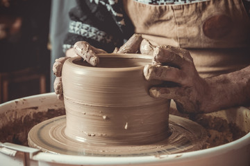 elderly man making pot using pottery wheel in studio