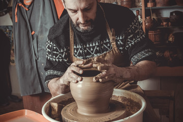 elderly man making pot using pottery wheel in studio