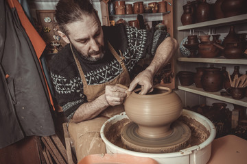 elderly man making pot using pottery wheel in studio