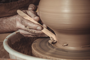 elderly man making pot using pottery wheel in studio