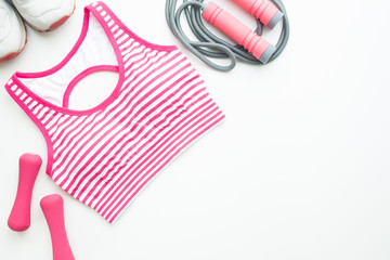 Sport bra, sneakers, sport and fitness equipments in pink color tone on white background with copy space