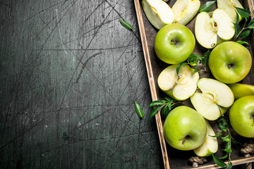 Fresh green apples on a wooden tray.