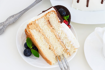 Piece of vanilla layer cake with fresh berries, cream cheese and chocolate biscuits.