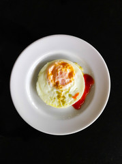 Fried eggs in a white plate ,Top view, black background.