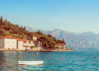 Fototapeta na wymiar Panorama of Boka-Kotorsky Bay with a fragment of the embankment of the ancient city of Perast, Montenegro. A view of the mountains from the waters of the Bay of Kotor on the Adriatic Sea.