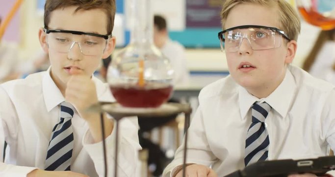 4K Young boys in school science class watching chemistry experiment with fascination