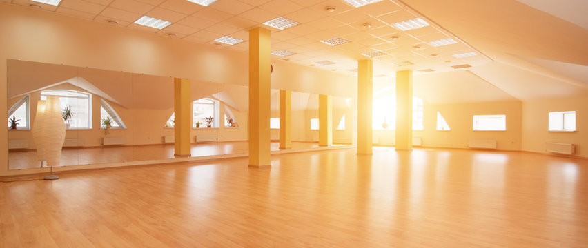 Perspective view of empty sunny yoga studio with wooden flooring