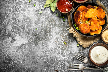 Chicken nuggets in a pan with different sauces.