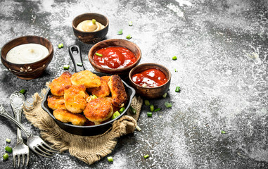 Fototapeta na wymiar Chicken nuggets in a pan with different sauces.