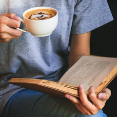 Young girl reading a book and drinking coffee