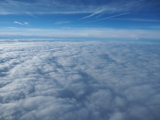 Landscape from the airplane window to a massive sea of clouds in a blue sky