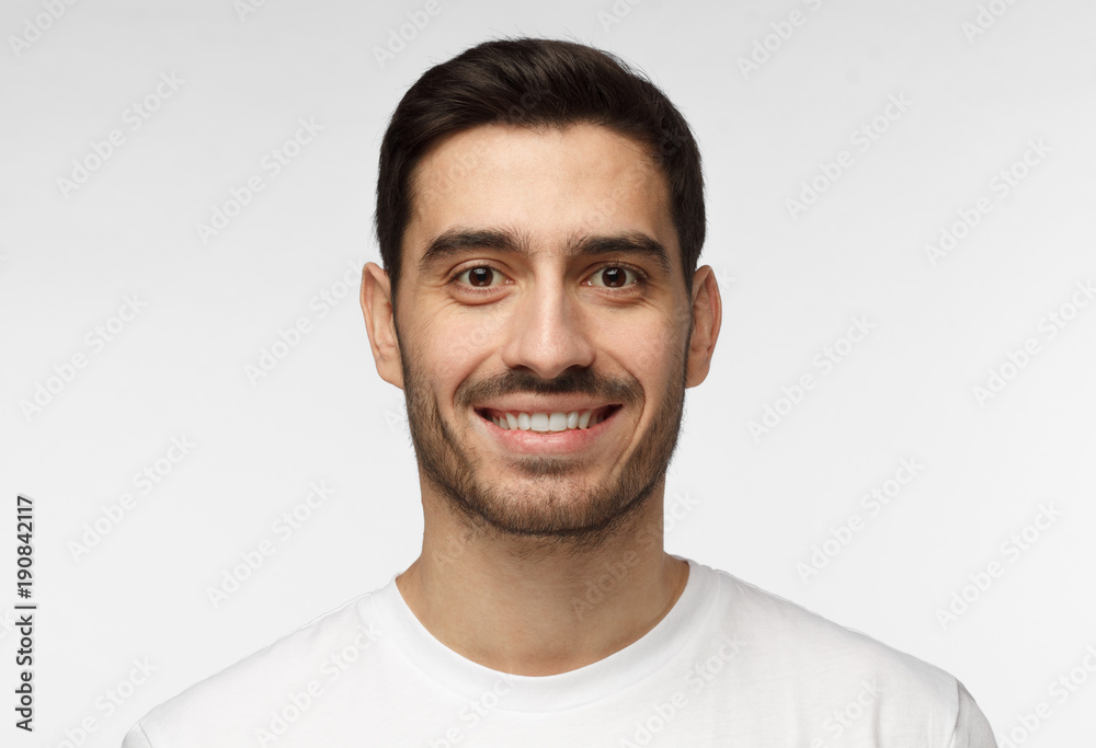 Wall mural Close up shot of young smiling man isolated on grey background