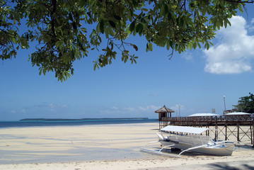 Seaside Scene with Outrigger and Boardwalk by a White Beach