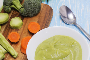 Broccoli cream soup on blue wooden table.