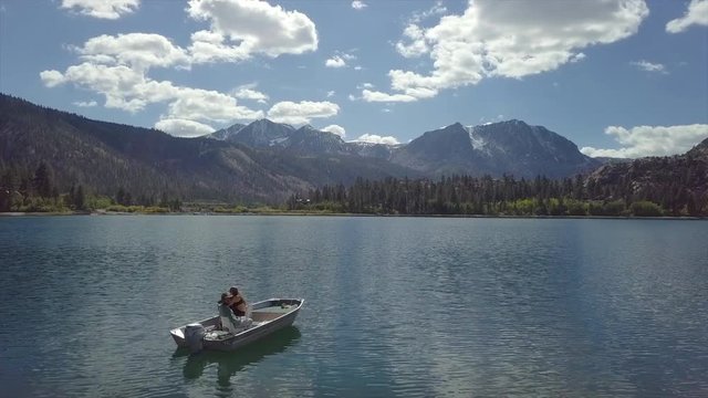 Aerial Reveal of couple fishing on boat Lake June Mountain background, Mono County - California 13