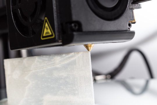 3D Printer Extruder Operation - Closeup view of a 3D printer's extruder in operation laying down white PVA plastic.