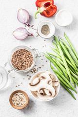 Healthy vegetarian food ingredients for lunch on a light background, top view. Buckwheat, green beans, sweet peppers, mushrooms, red onion - clean eating vegetarian food concept