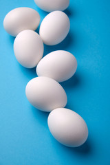 Fresh white eggs over blue background, top view.