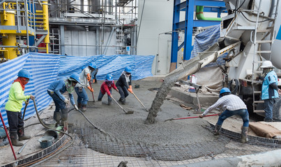 Workers at the construction site placing concrete slab