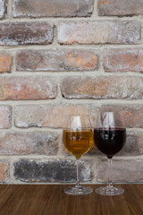 Glasses with red and white wine. Red and white wine glasses on a old brick wall.