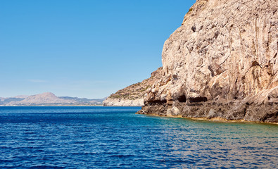 Coastal cliffs. Deep blue sea water. Coast of the Mediterranean Sea. Rhodes, Greece.