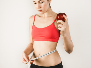 Young woman measuring a waist with a centimeter tape after training. Sport, fitness, health