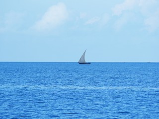 Island in the Indian Ocean, boat in the ocean, sailboat in the ocean, beautiful Indian ocean, beautiful landscape, horizon of the earth, beautiful sky, calm ocean, blue sky,