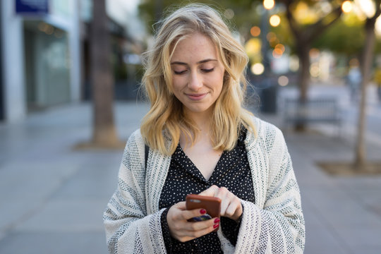 Young caucasian woman walking texting on cell phone