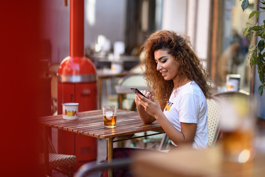 Arab Woman In An Urban Bar At Her Smartphone.