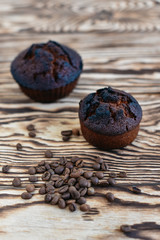 Fresh delicious cupcake and coffee fragrant grains on a wooden background