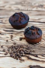 Fresh delicious cupcake and coffee fragrant grains on a wooden background