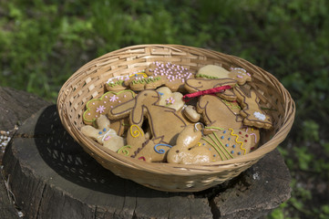 Czech easter gingerbread in wicker basket in the garden brown wooden stump, comical bunnies