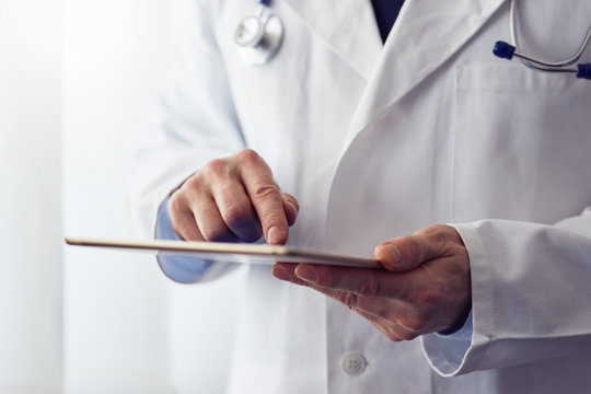 Male doctor presses on screen digital tablet