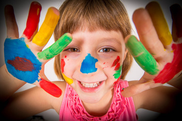 smiling little girl with hands painted in colorful paints