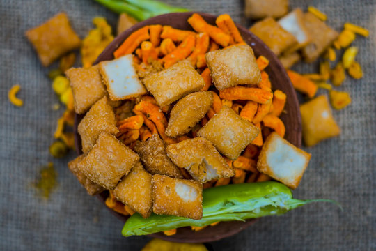 Close up of Indian appetizers i.e chevdo, & Shakkarpara in a  small container on gunny background