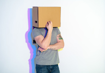 Thoughtful male with painted reflection hiding face inside pasteboard box. Dreaminess concept