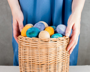 Woman holding the basket with colored yellow easter eggs