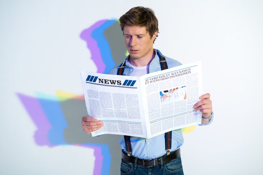 Portrait of calm male reading interesting article while holding it in hands. Multicolored shadow. Publication concept