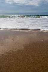 Foamy atlantic ocean wave on beach sand.